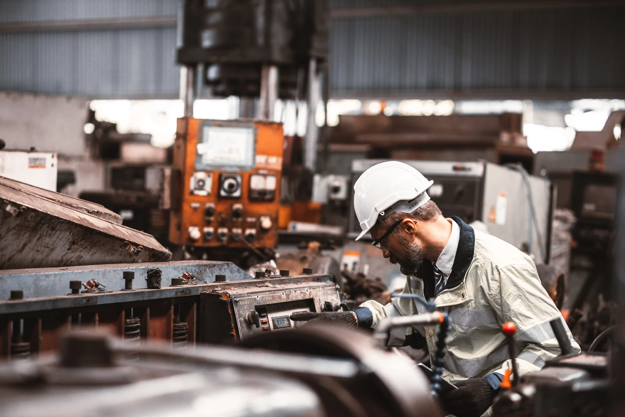 Engineer in a hard hat inspecting industrial machinery